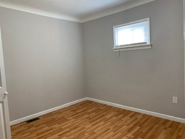an empty room with a window and a wooden floor