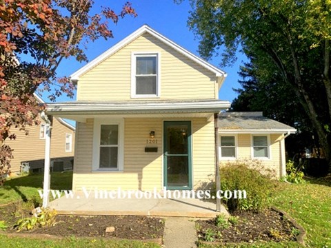 a yellow house with a front yard and trees