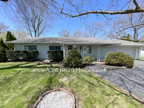a small blue house with a yard and a tree