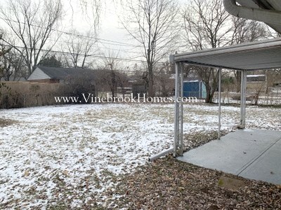 a snow covered yard with a covered pavilion
