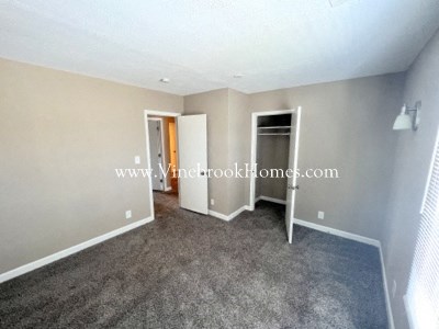 a large living room with a carpet and a door to a closet