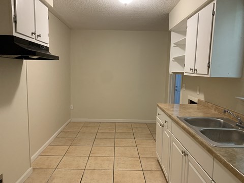 A kitchen with white cabinets and a beige tile floor.