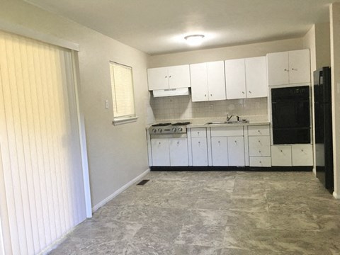 A kitchen with white cabinets and a black oven.