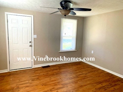 an empty living room with a ceiling fan and a door