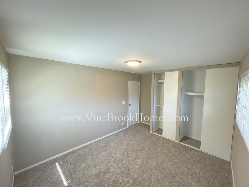 a bedroom with white walls and a closet and a carpeted floor