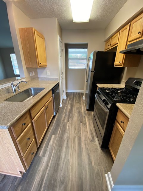 A kitchen with wooden cabinets and a black refrigerator.