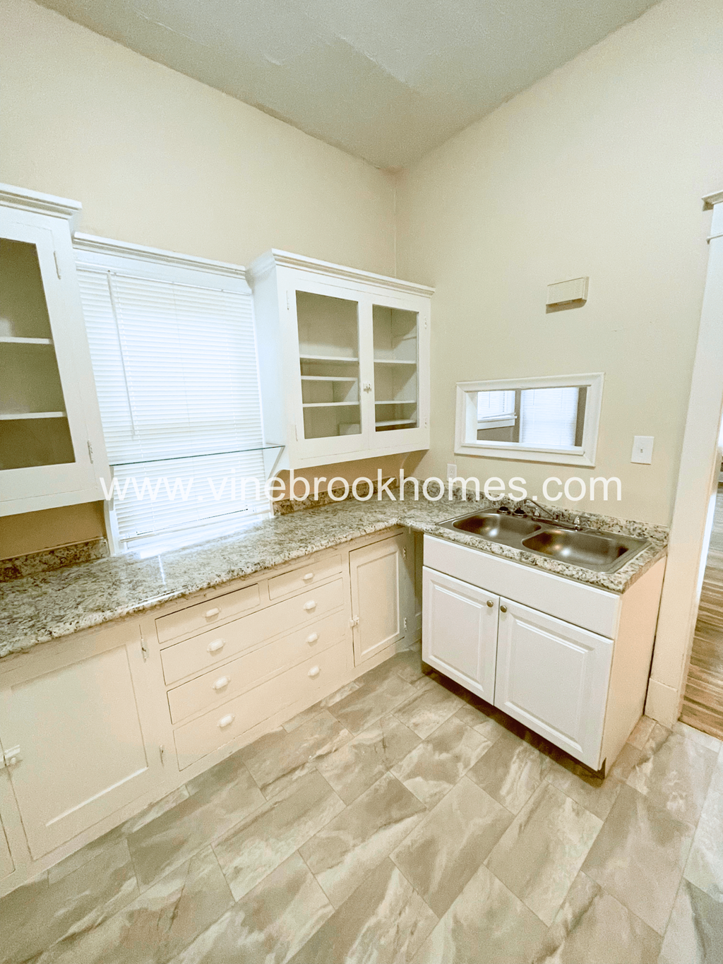 a kitchen with white cabinets and granite counter tops