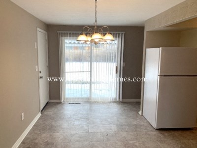 an empty kitchen with a refrigerator and a window