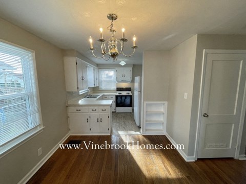 A kitchen with white cabinets and a chandelier.