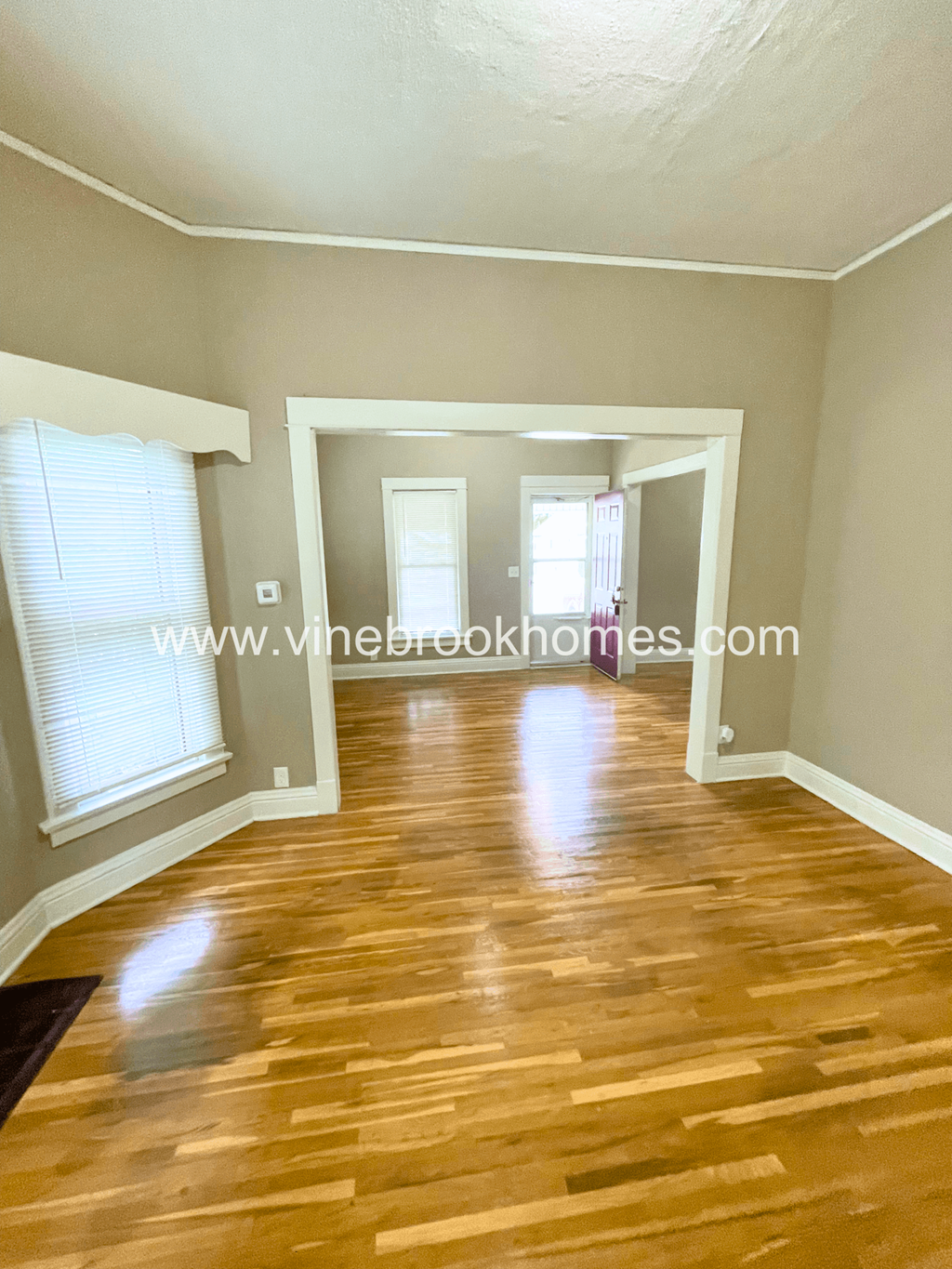 an empty living room with a hard wood floor and a window
