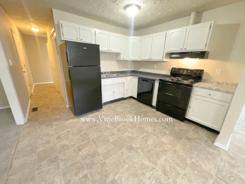 a white kitchen with black appliances and white cabinets