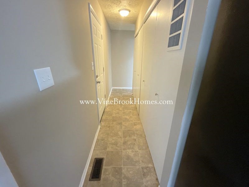 a long hallway with a door to a closet and a white door