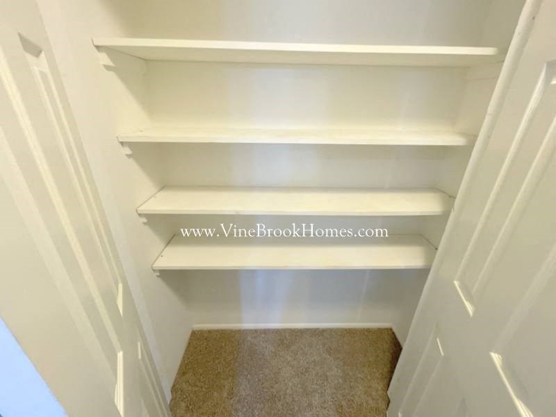 three white shelves in a closet in a white door
