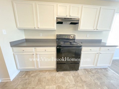 A black stove in a kitchen with white cabinets.