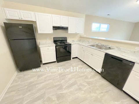 A kitchen with black appliances and white cabinets.