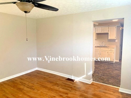 an empty living room with wood floors and a ceiling fan