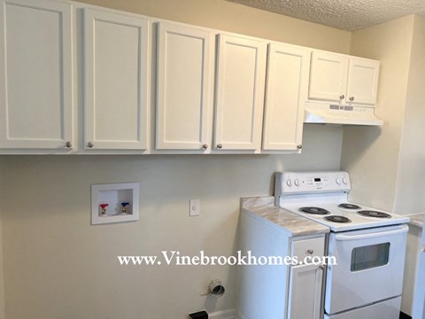 A kitchen with white cabinets and a white stove top oven.