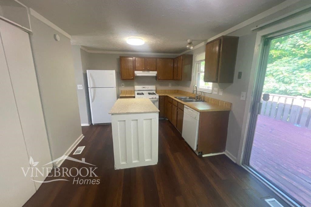 a small kitchen with wooden floors and white appliances