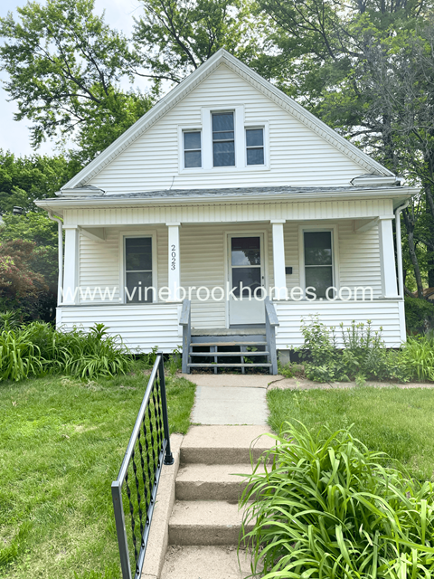a small white house with a porch and stairs