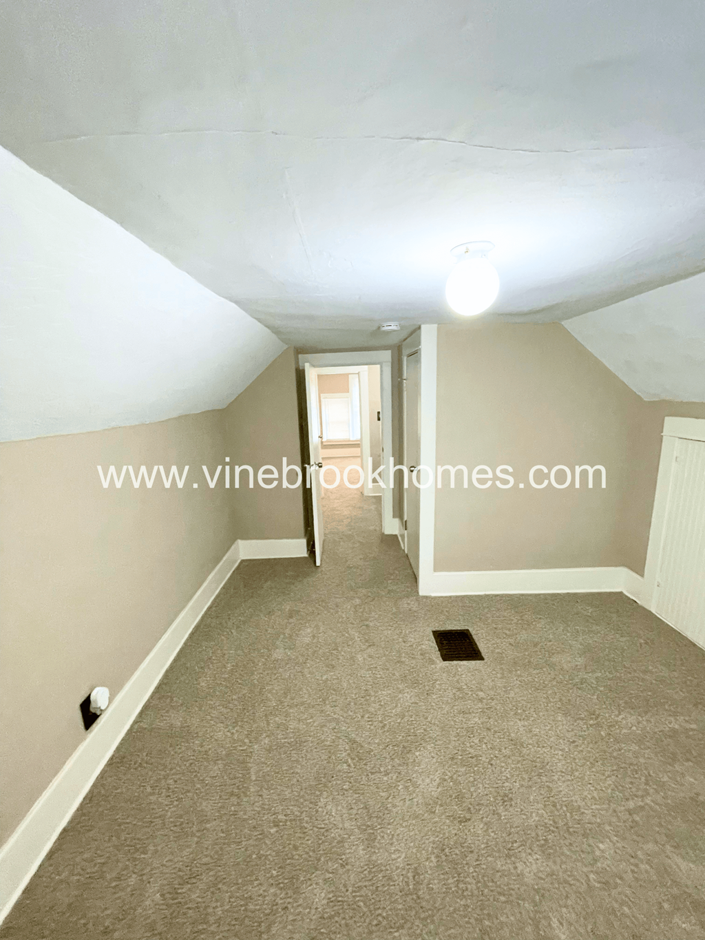 a small carpeted hallway with a door to a closet and a window
