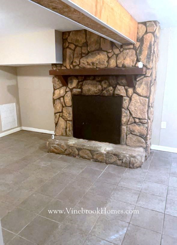 a large stone fireplace in a living room with a tile floor