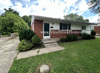 a small brick house with a front porch and grass