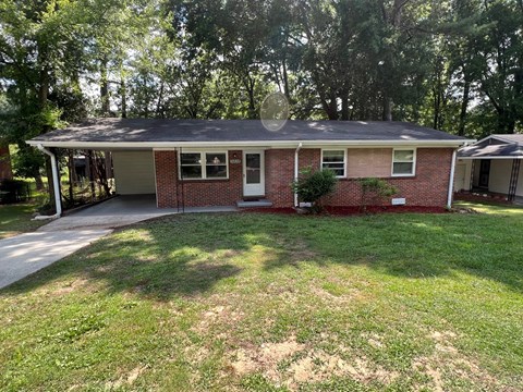 a small brick house with a porch and a lawn