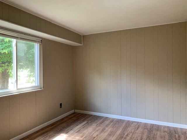 an empty room with wood floors and a window