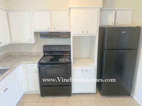 A black stove and oven in a kitchen with white cabinets.