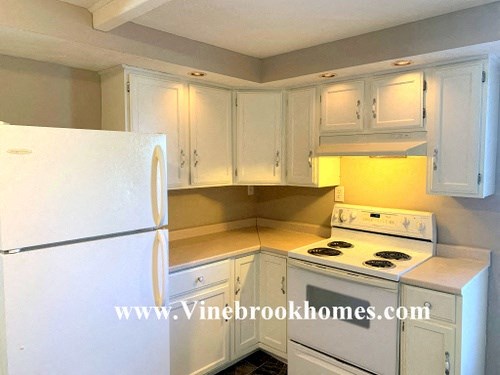 a kitchen with white cabinets and a refrigerator
