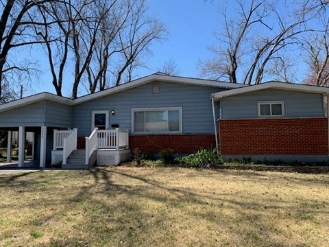 a blue house with a brick porch and a lawn
