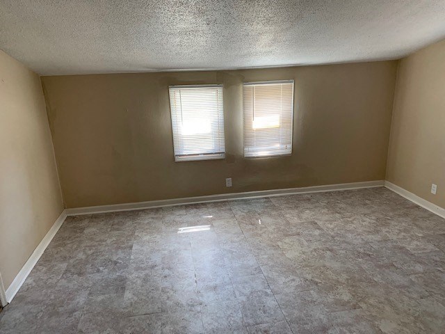 an empty room with two windows and a tile floor