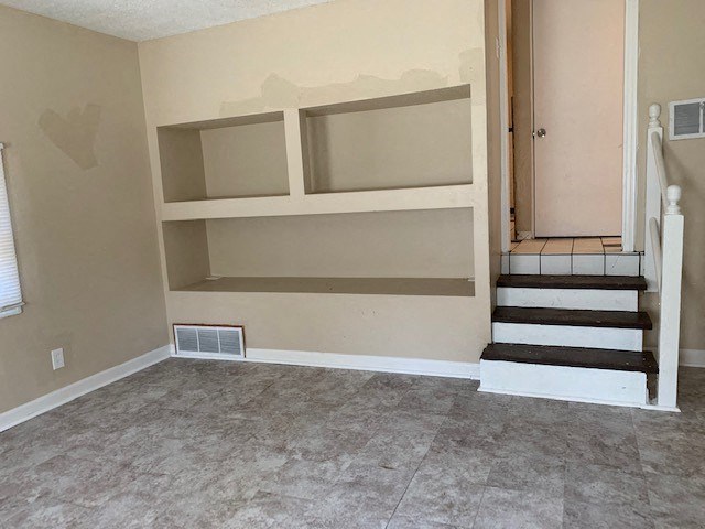 a room with a staircase and shelves in it