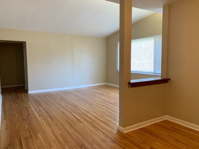 an empty living room with wood floors and a window