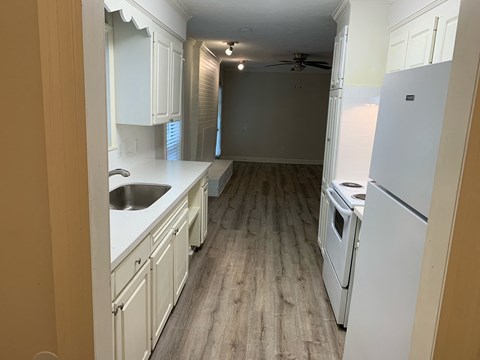 a kitchen with white cabinets and white appliances and wood floors