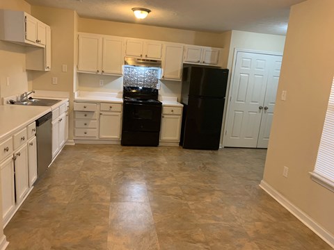 A kitchen with a black refrigerator and white cabinets.