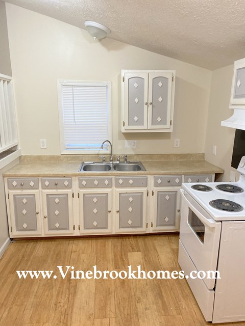 a kitchen with white cabinets and a sink and a stove