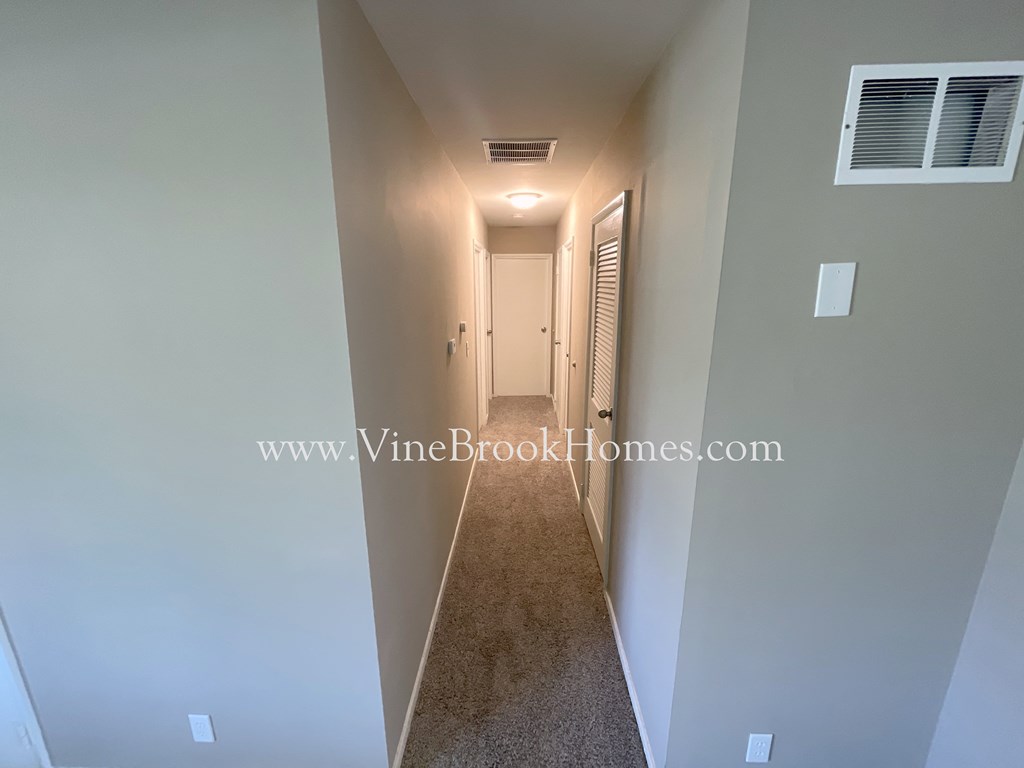 a long hallway with a door to a closet and a window