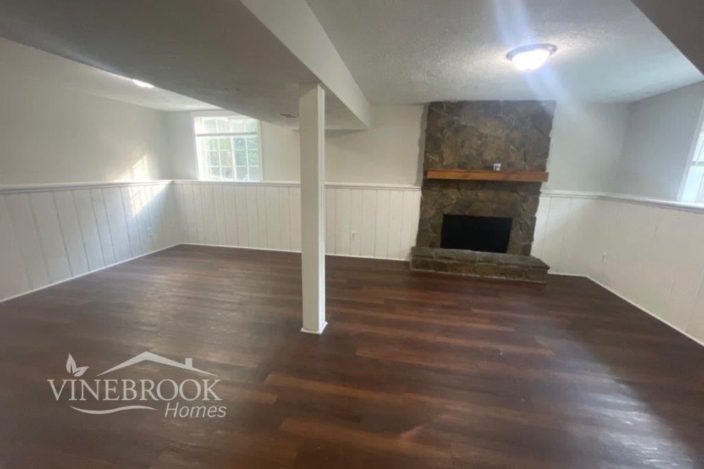 the living room of the home has a fireplace and wooden floors