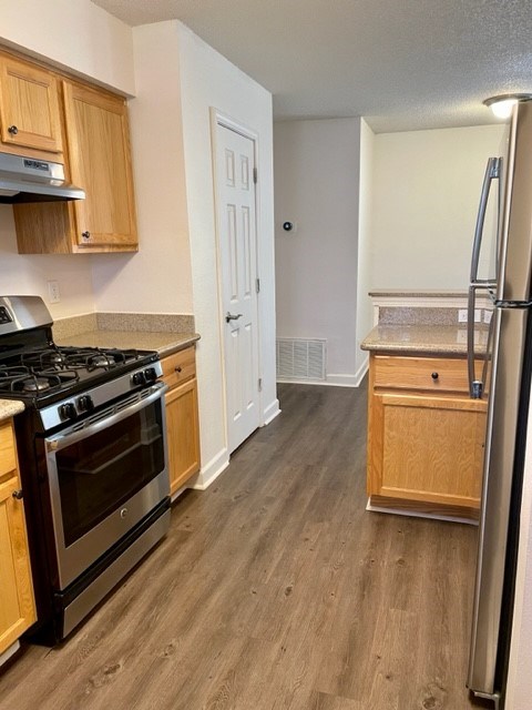 A kitchen with a black stove top oven and wooden cabinets.