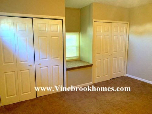 an empty room with two closets and a window and white doors