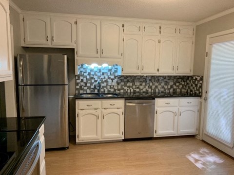 A kitchen with white cabinets and a black countertop.
