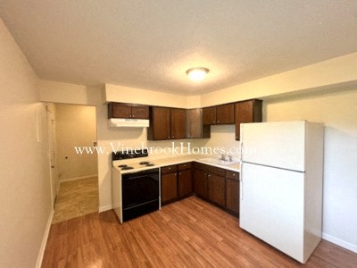 A kitchen with white appliances and wooden floors.