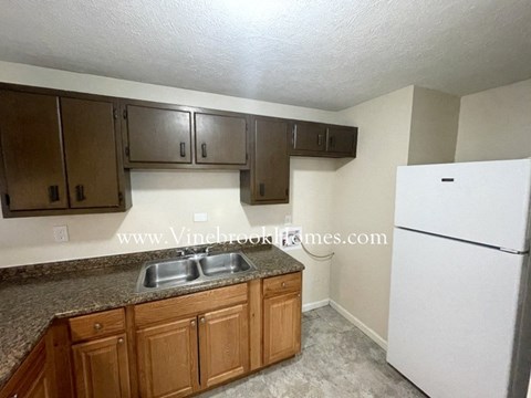 A kitchen with brown cabinets and a white fridge.