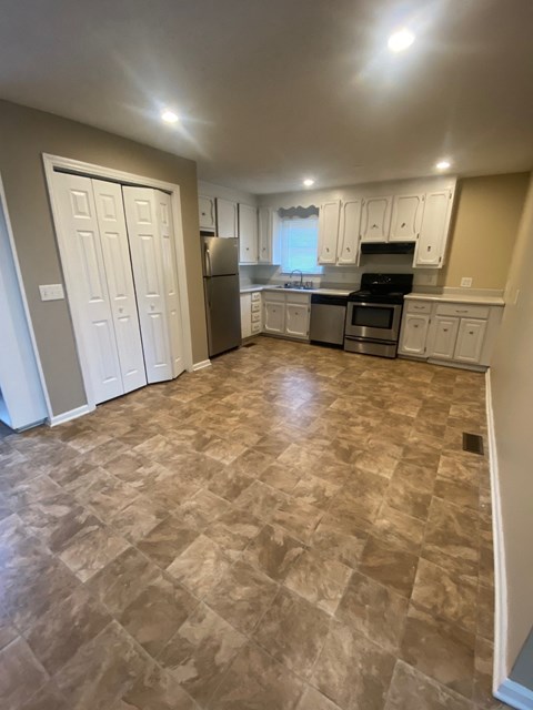 A kitchen with tile flooring and white cabinets.