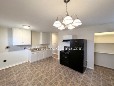A kitchen with a black fridge and a tiled floor.