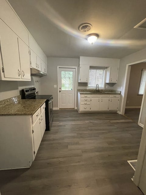 a renovated kitchen with white cabinets and a wood floor