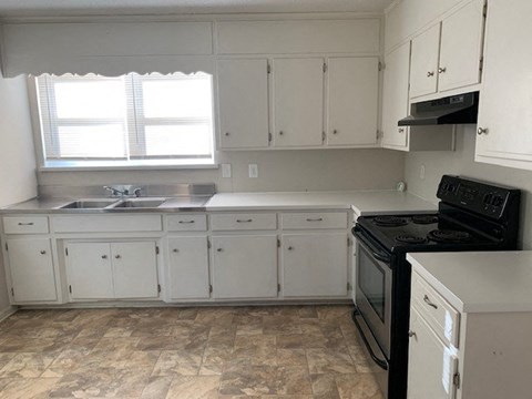 A kitchen with white cabinets and a black stove top oven.