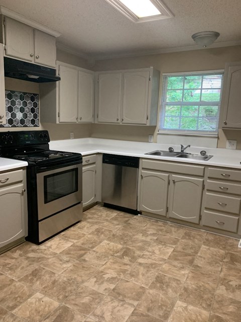 A kitchen with a black stove top oven and white cabinets.