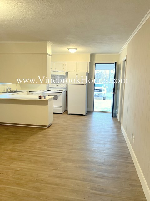 a small kitchen with white cabinets and a door to a patio